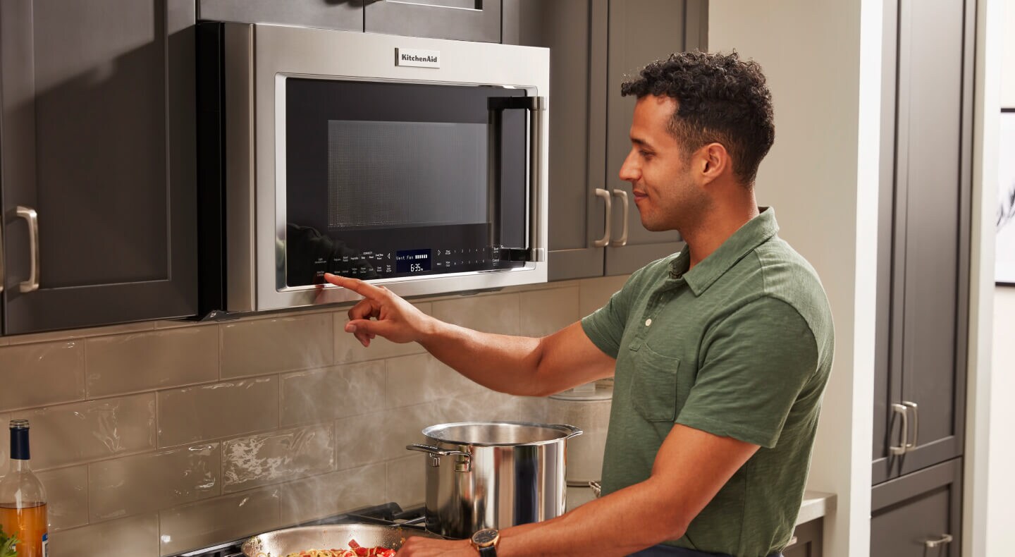 Person selecting settings on a KitchenAid® over-the-range microwave