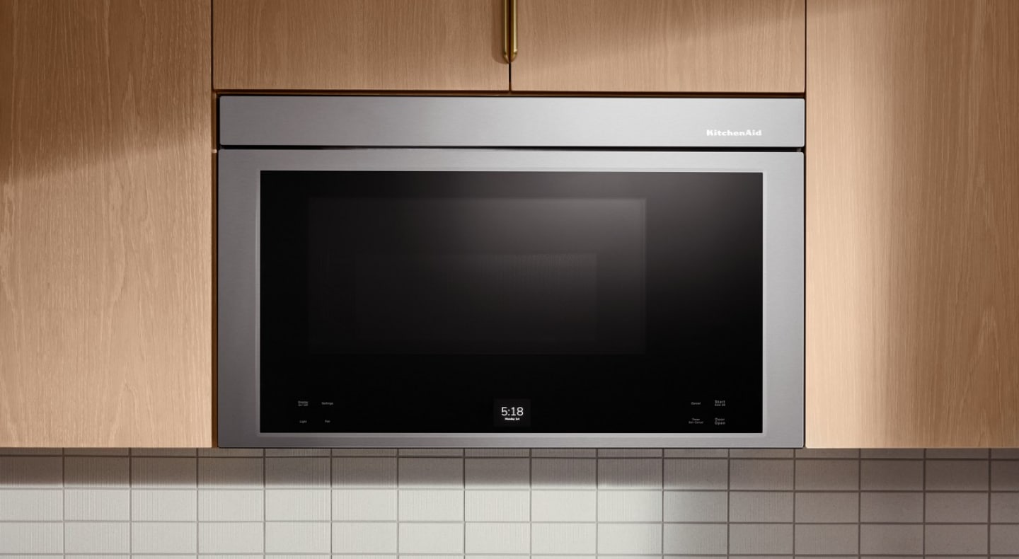 Stainless KitchenAid® over-the-range microwave in light brown cabinetry