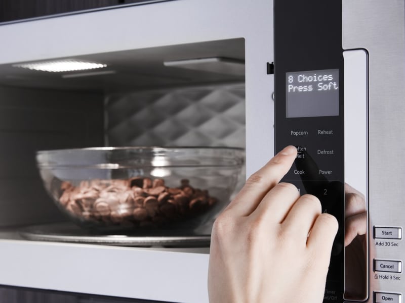 Person selecting settings to melt chocolate chips in the microwave