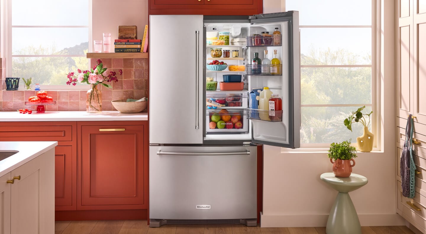An opened KitchenAid®  French door refrigerator in a rustic kitchen