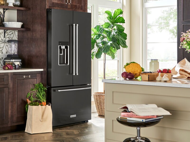 A black stainless steel KitchenAid® French door refrigerator with a bag of fresh produce beside it A black stainless steel KitchenAid® French door refrigerator with a bag of fresh produce beside it