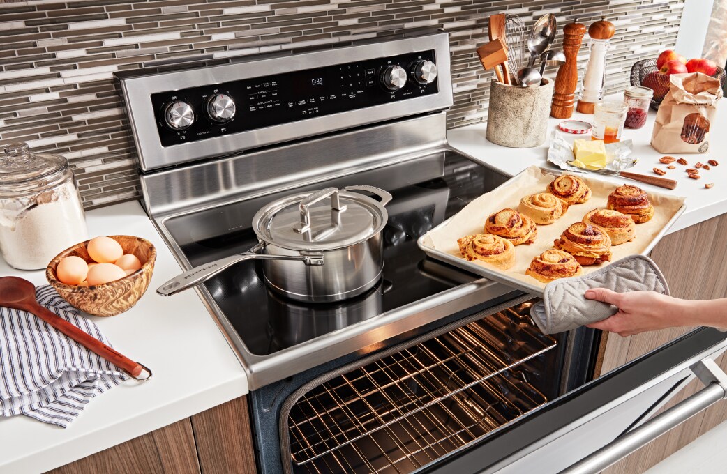 A person cooking on a KitchenAid® cooktop.