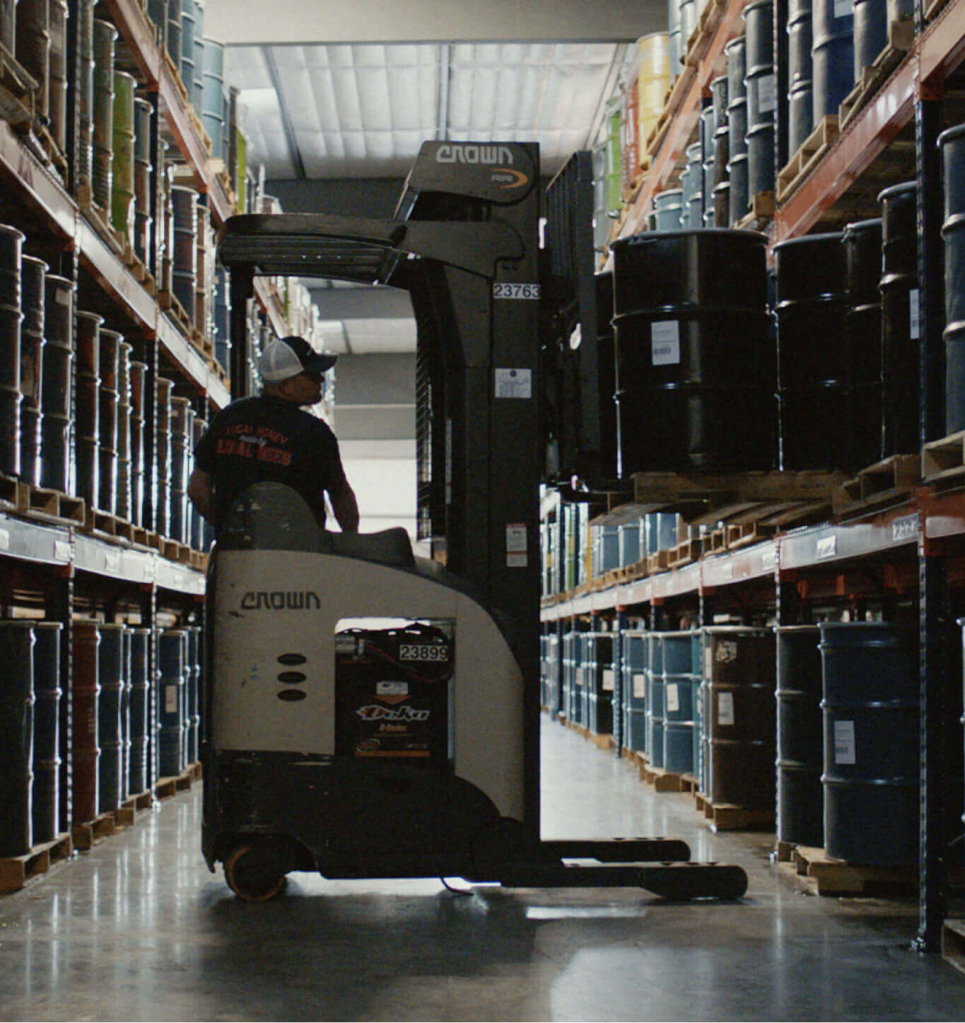 A man operating a forklift carrying barrels of honey.