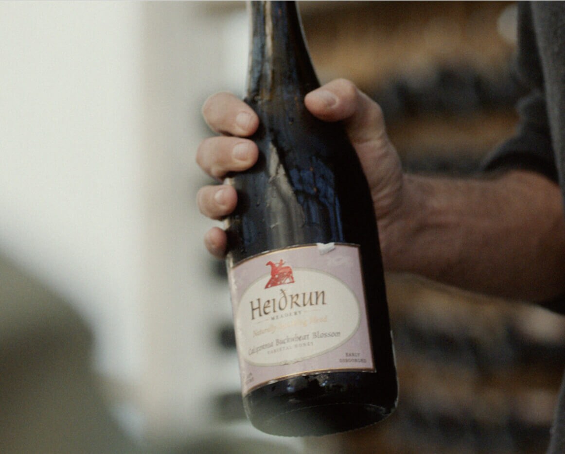 A person holding a bottle of mead.