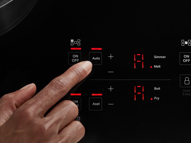 Person selecting a cooking setting on an induction cooktop