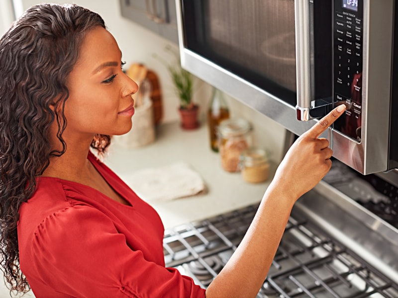 Person pushing buttons on a microwave