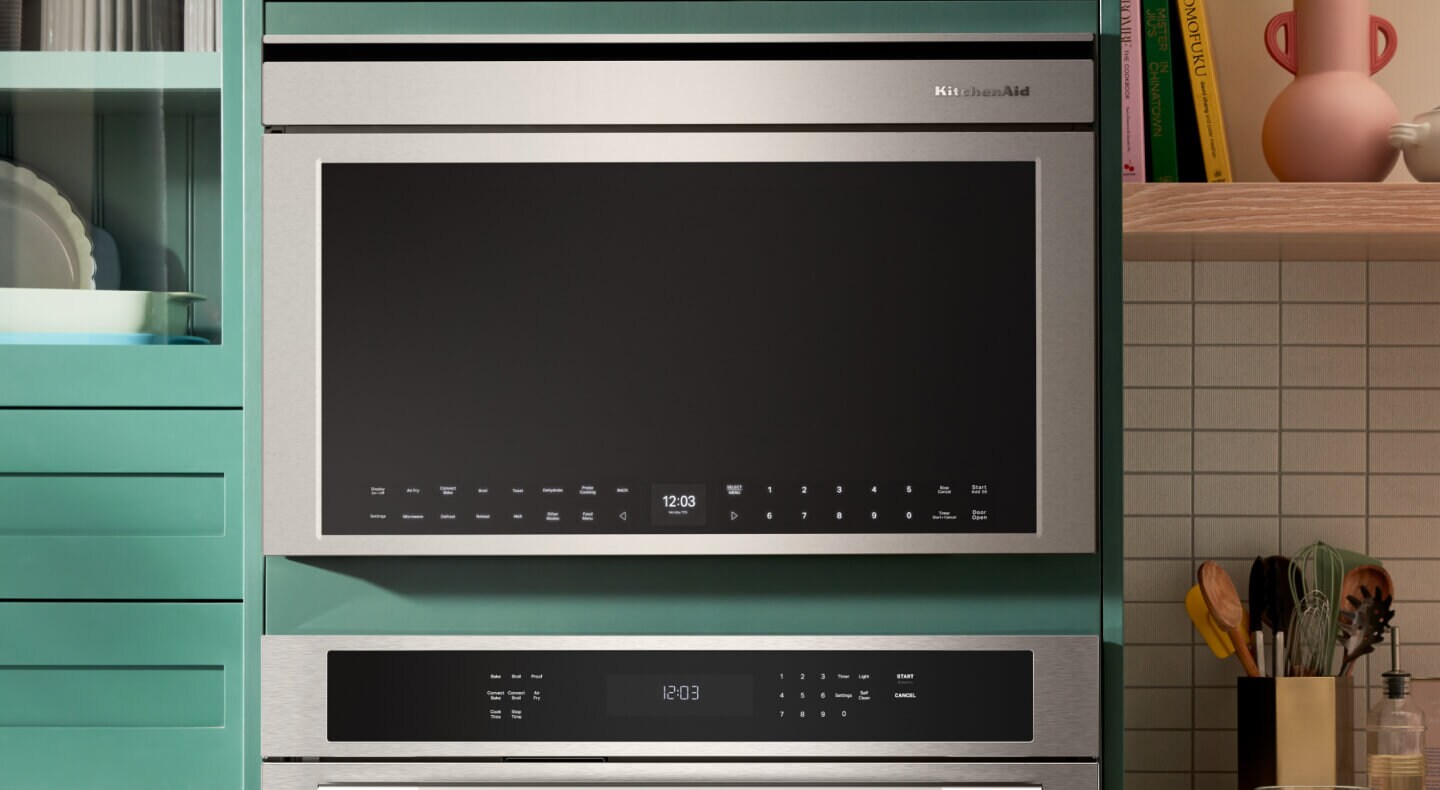 Person placing a plate of food in an over-the-range microwave