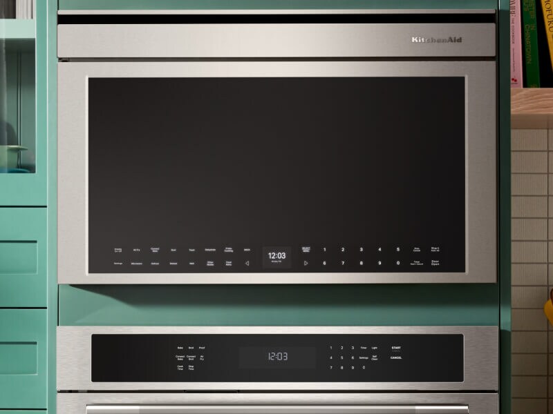 Person placing a plate of food in an over-the-range microwave