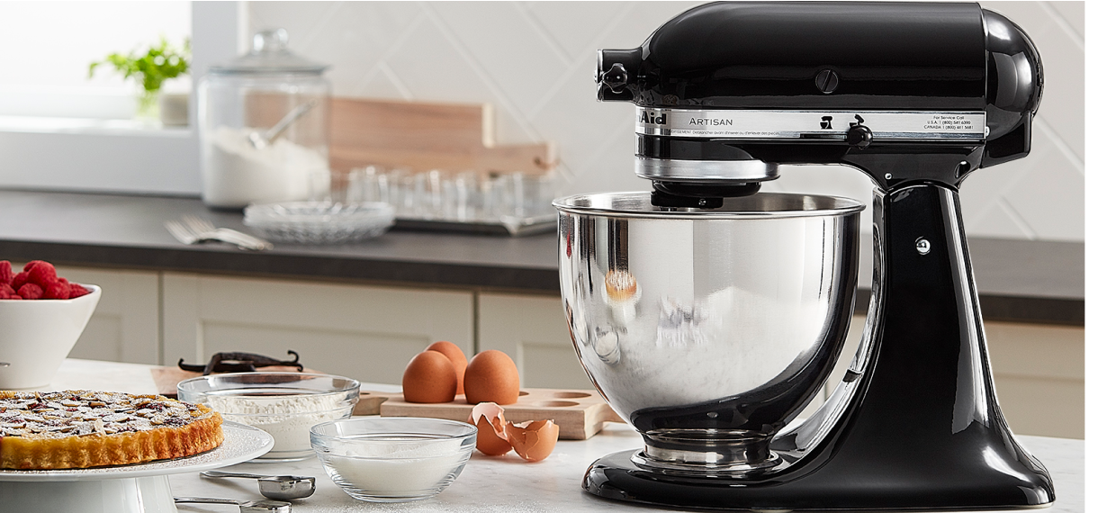 A hand blender with avocados and peppers on the counter.