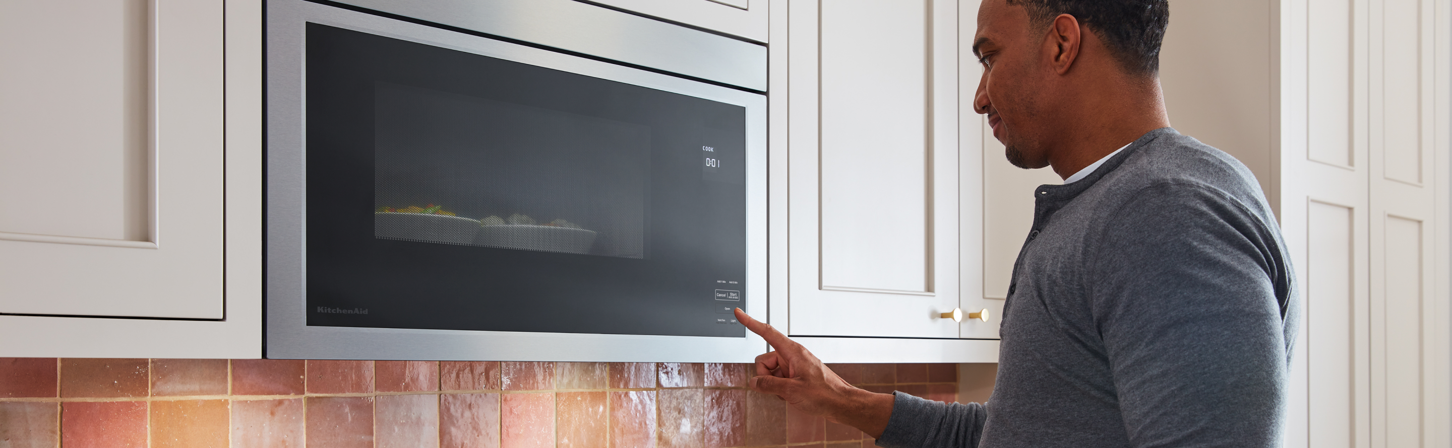 A person touching a button on KitchenAid® microwave.