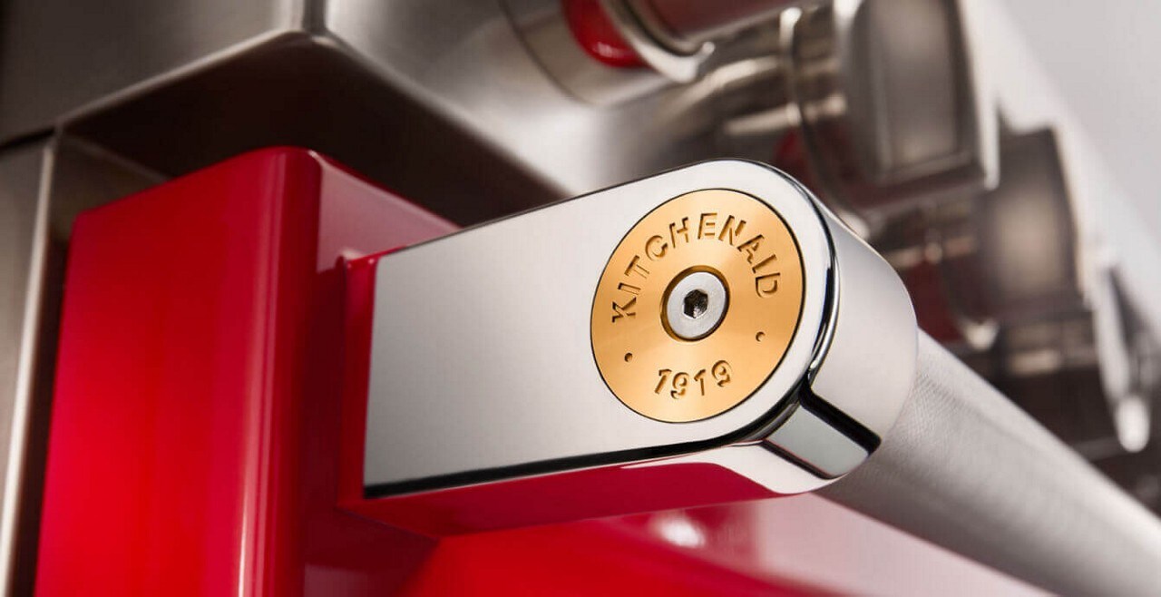 Close-up of a commercial-style range and handle equipped with a gold medallion.