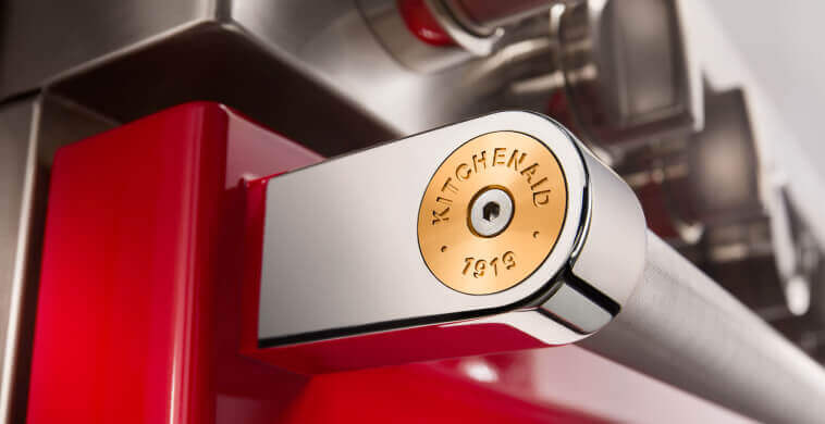 Close-up of a commercial-style range and handle equipped with a silver medallion.