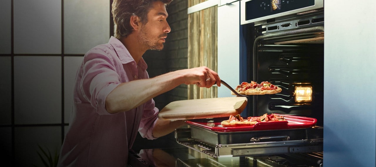 A man plating two flatbread pizzas from his KitchenAid® smart wall oven.