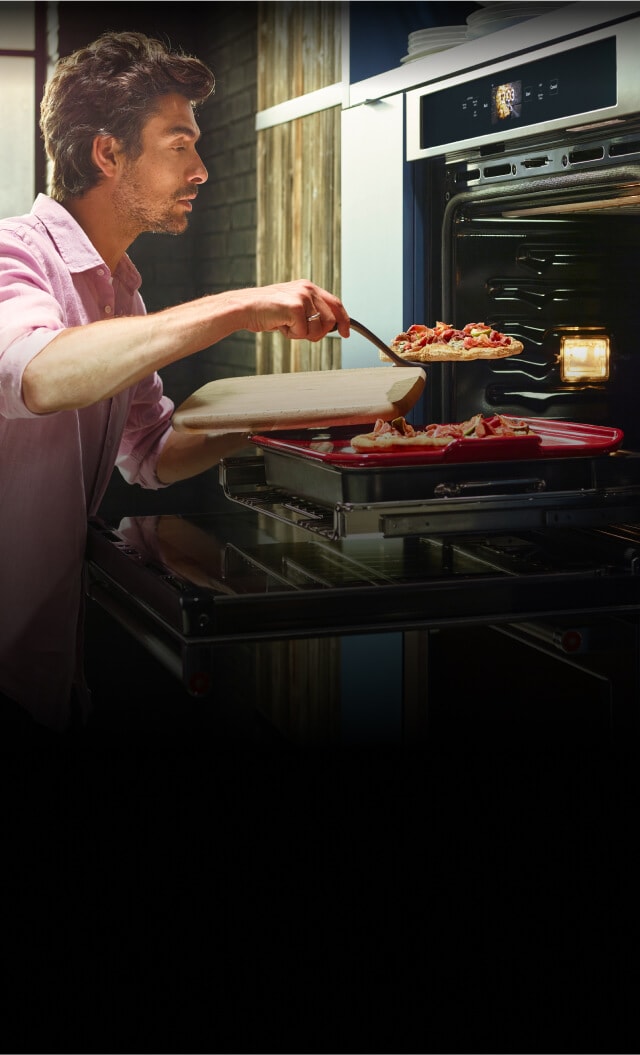 A man plating two flatbread pizzas from his KitchenAid® smart wall oven.