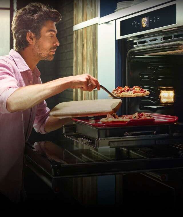 A man plating two flatbread pizzas from his KitchenAid® smart wall oven.