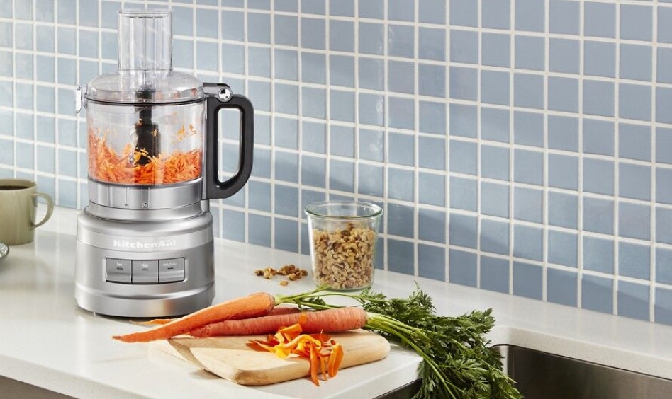 Silver KitchenAid® Food Processor on counter with carrots and blue backdrop Silver KitchenAid® Food Processor on counter with carrots and blue backdrop