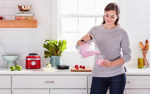 Woman pouring a smoothie from a blender jar 