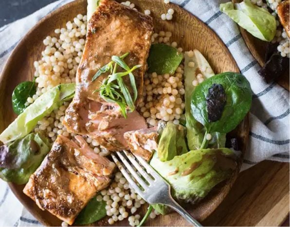 Plate of roasted salmon on bed of couscous and greens. Plate of roasted salmon on bed of couscous and greens.