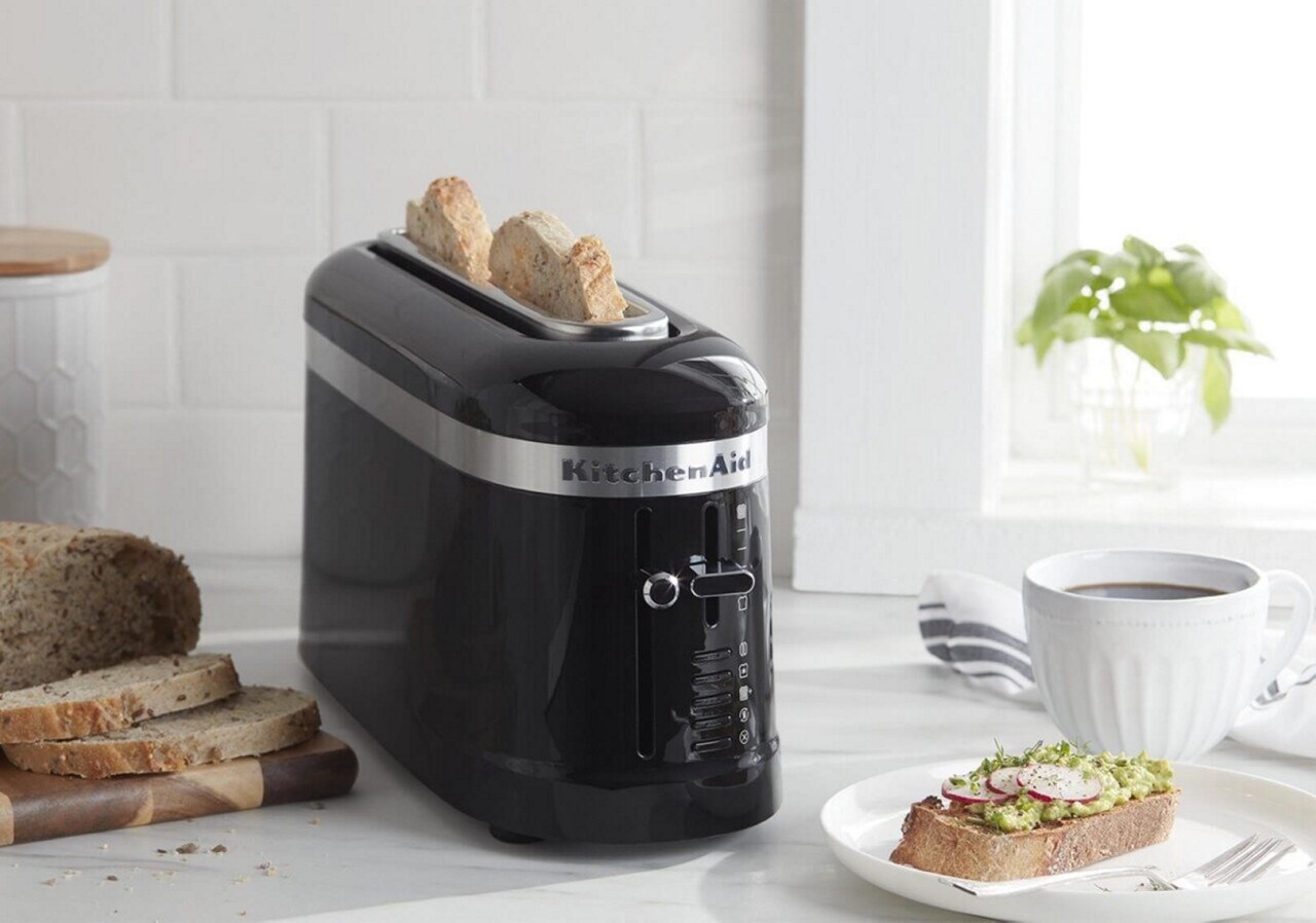 Black 2-slice toaster on counter with avocado toast Black 2-slice toaster on counter with avocado toast