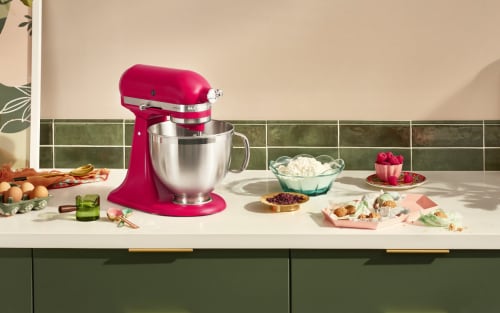 A pink KitchenAid® Stand Mixer on a countertop with eggs and other ingredients nearby