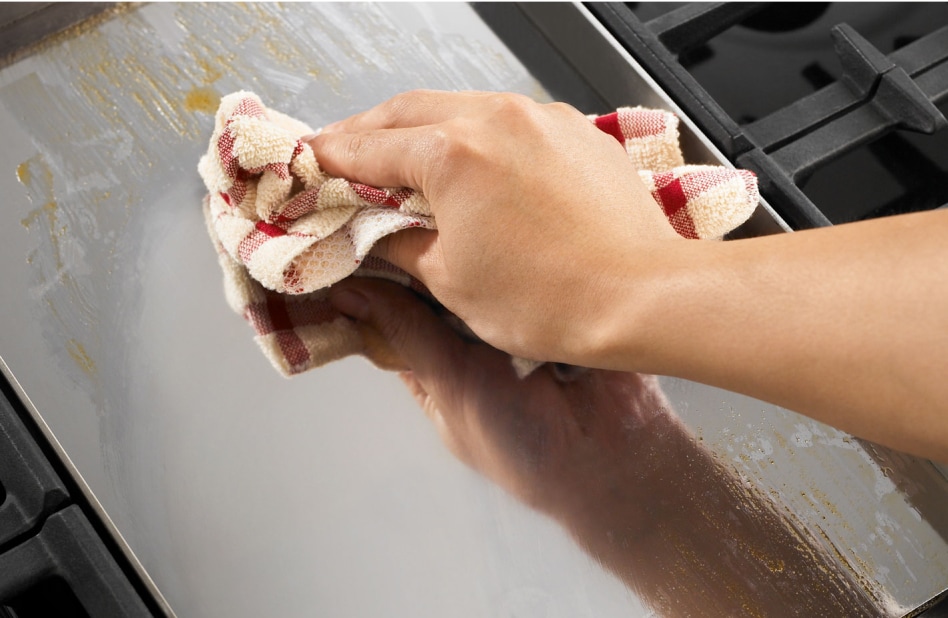 A flat cooktop surface being cleaned with a red and white cloth A flat cooktop surface being cleaned with a red and white cloth