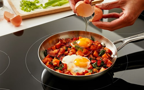 Eggs and veggies cooking in a pan on a stovetop