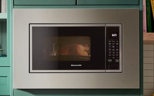 A built-in KitchenAid® microwave surrounded by teal cabinetry