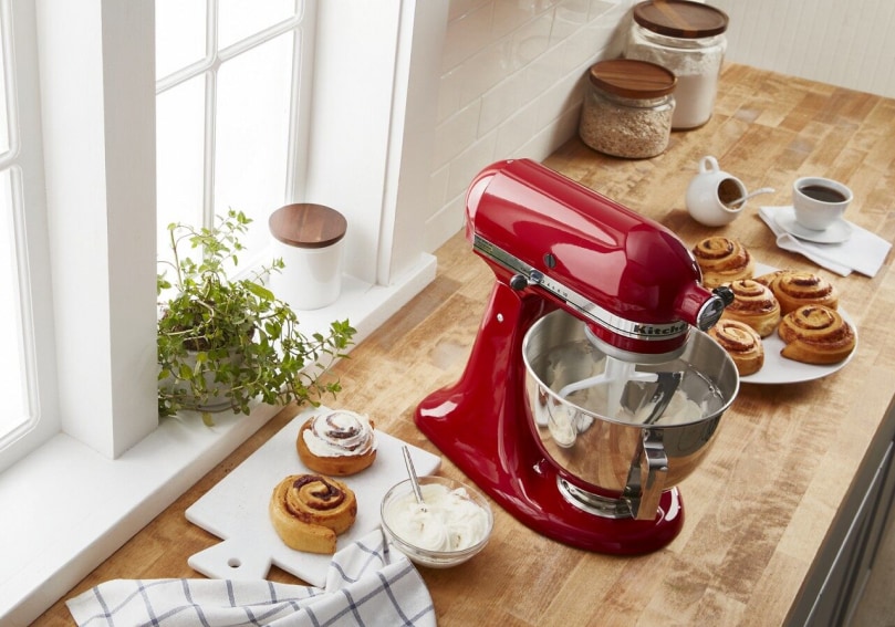 Red KitchenAid® stand mixer with flat beater attachment in bowl on butcher block countertop