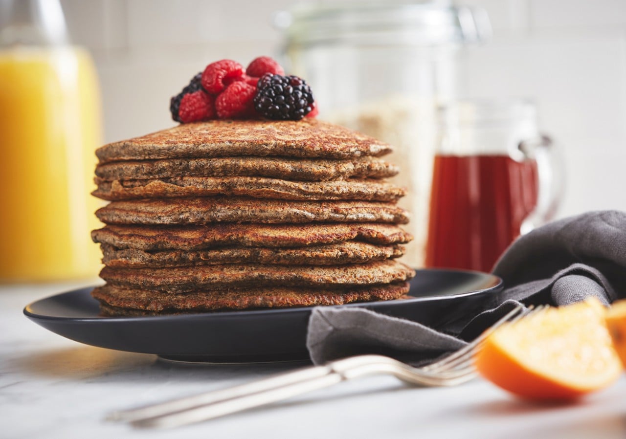 Stack of pancakes with berries on top on black plate