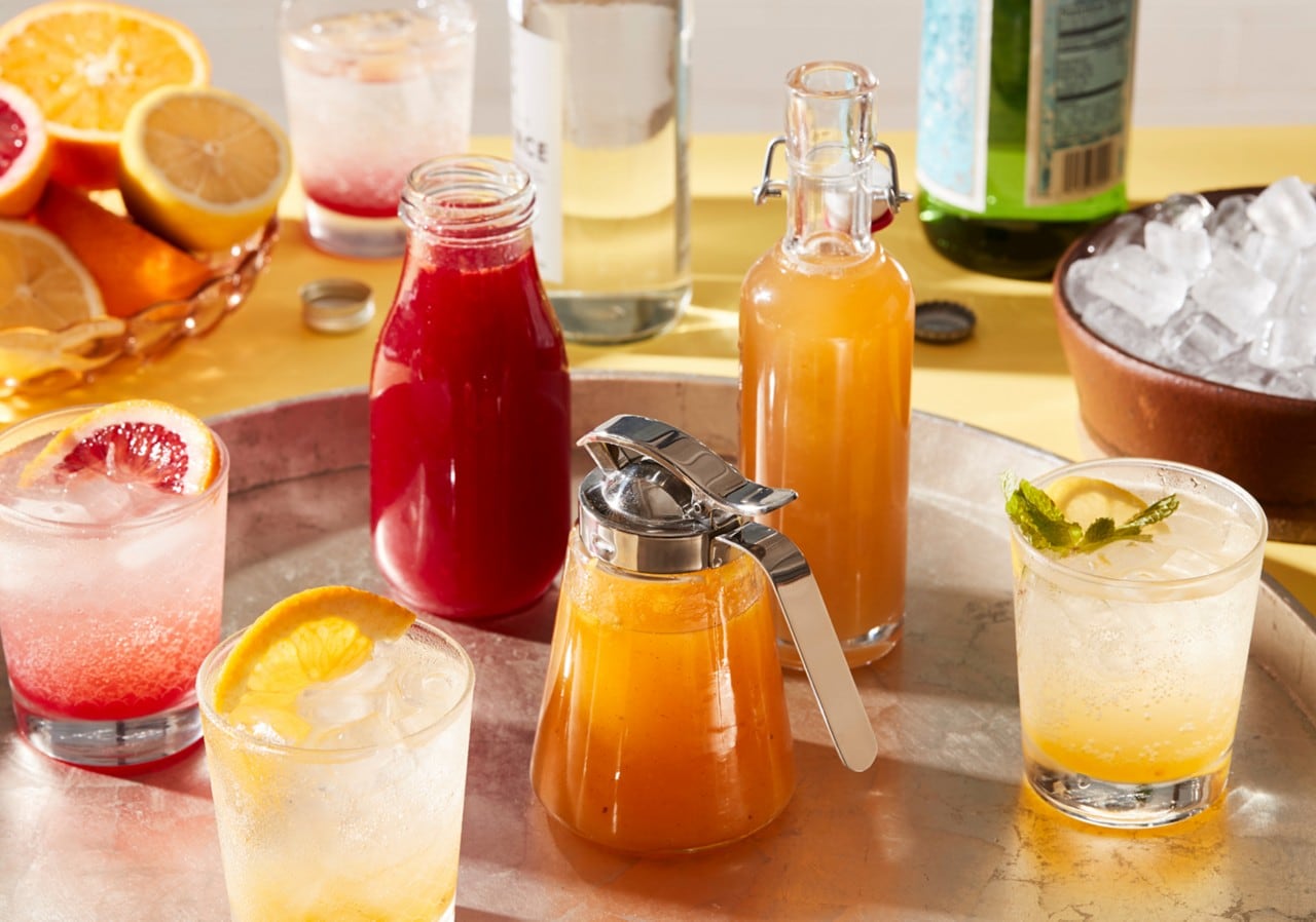Red, orange, and yellow fresh juices in pitchers and glasses