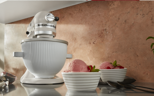 White KitchenAid® stand mixer with ice cream maker attachment next to bowls of strawberry ice cream