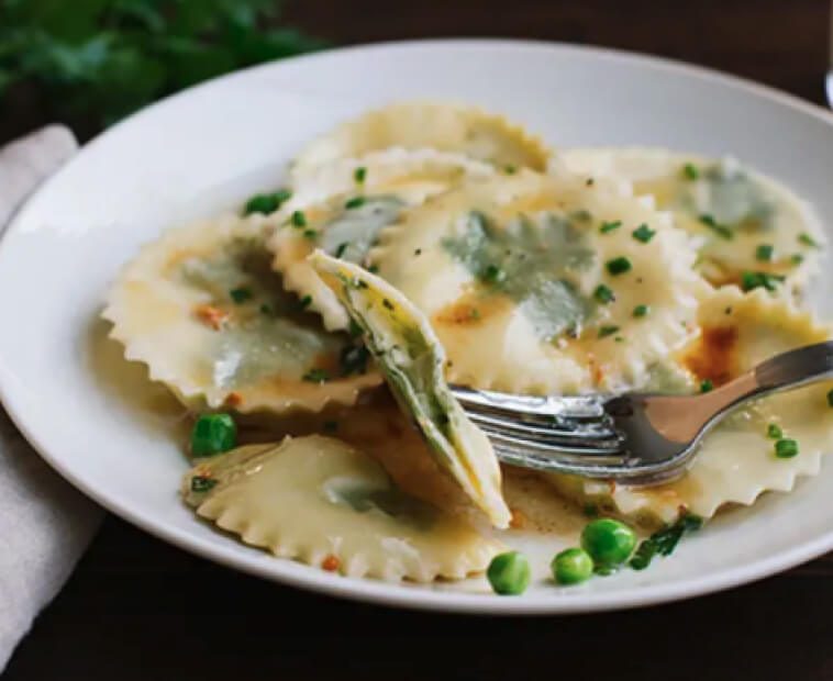 White plate with ravioli with parsley and peas. White plate with ravioli with parsley and peas.