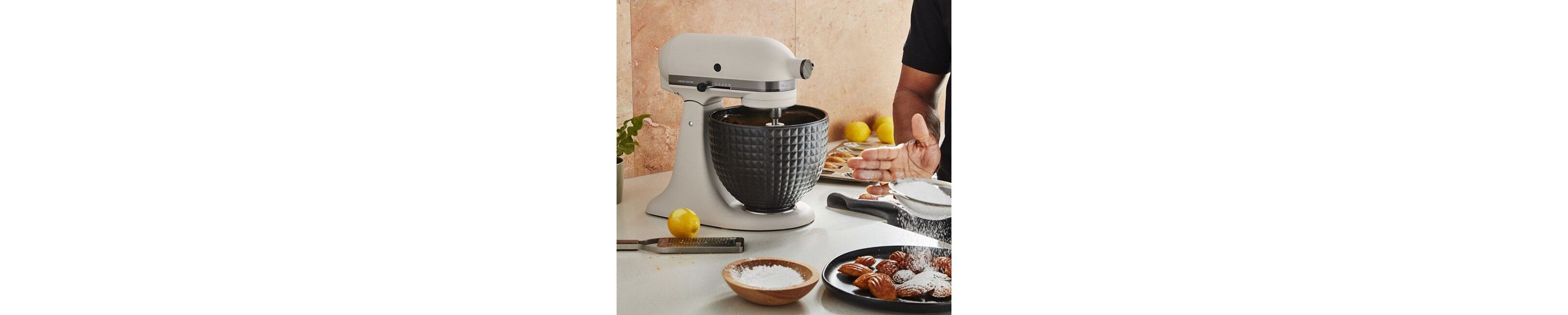 A Limited Edition Stand Mixer with Black Stainless Bowl on a kitchen counter next to waffles.