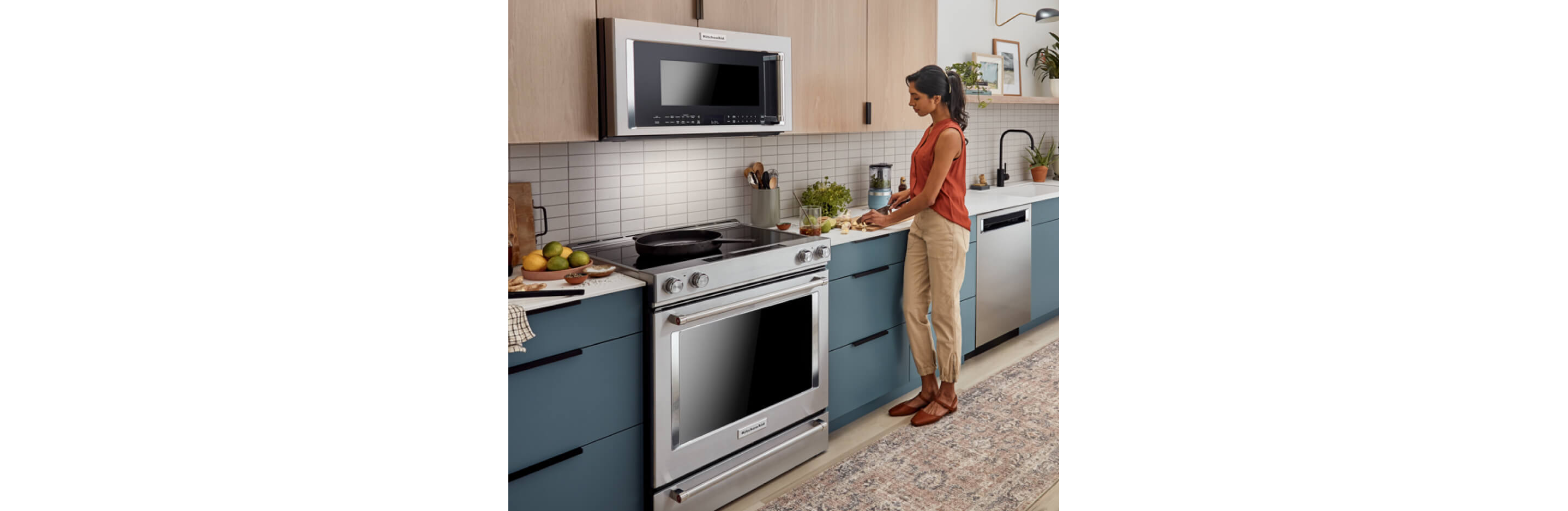 A person cutting up fruits in a modern kitchen that features a suite of KitchenAid® major appliances. 