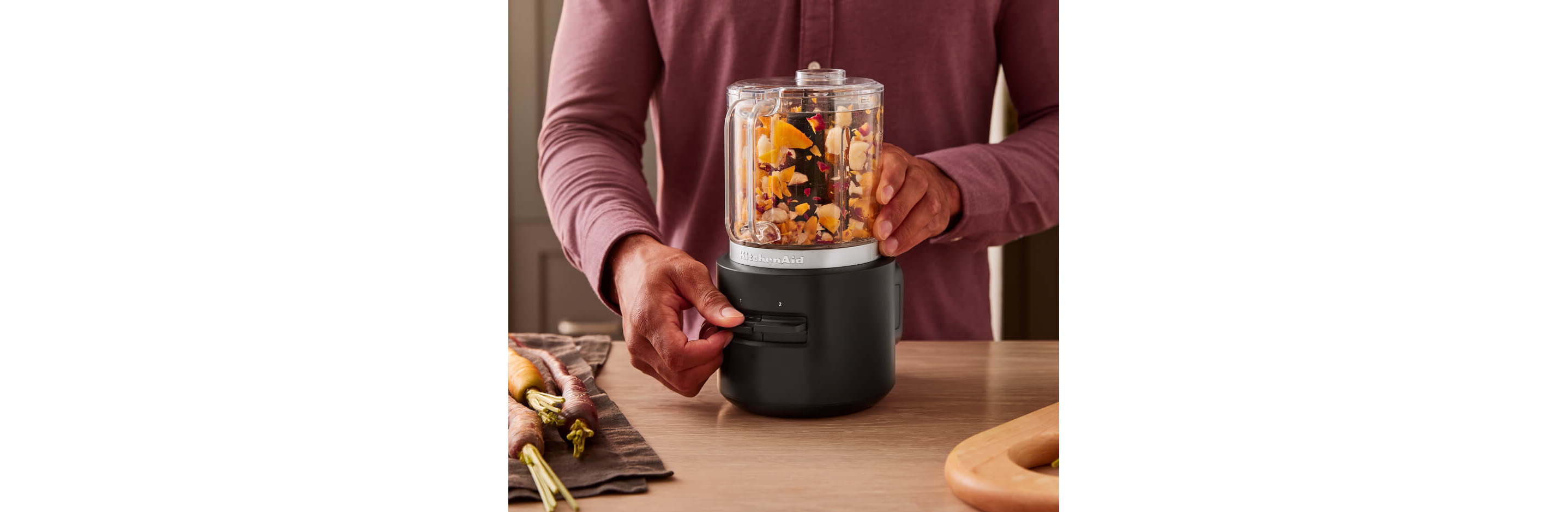 A person using a cordless food processor to chop up dried fruits and nuts. 