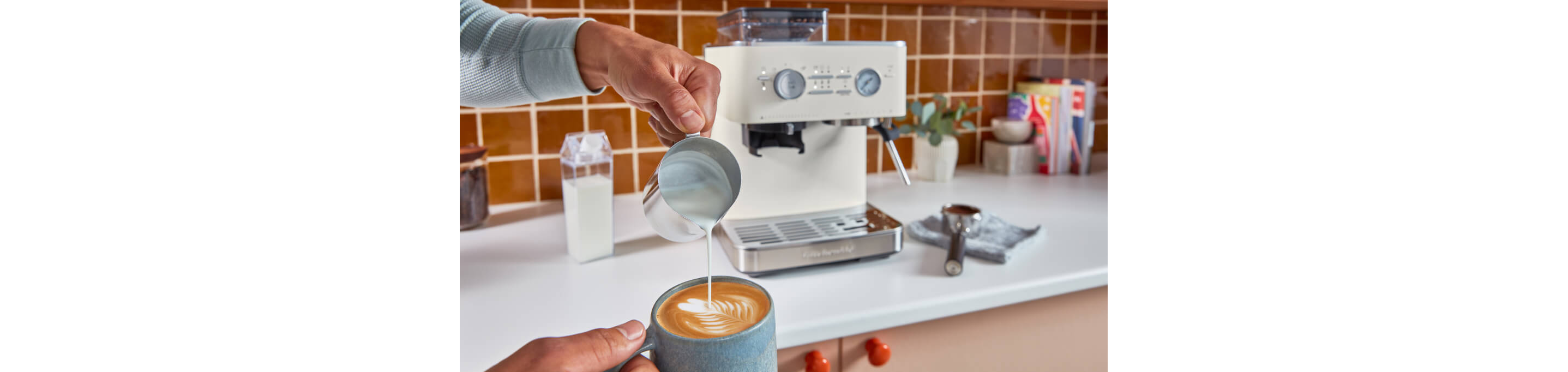 A person pouring steamed milk into an espresso drink.