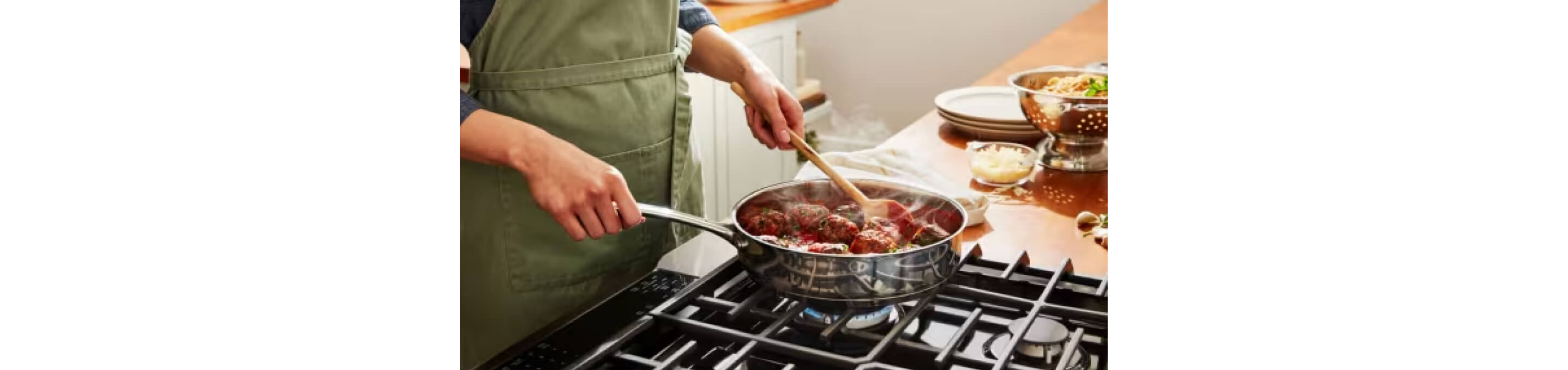A person cooking a meal in a stainless steel pan over a gas burner.
