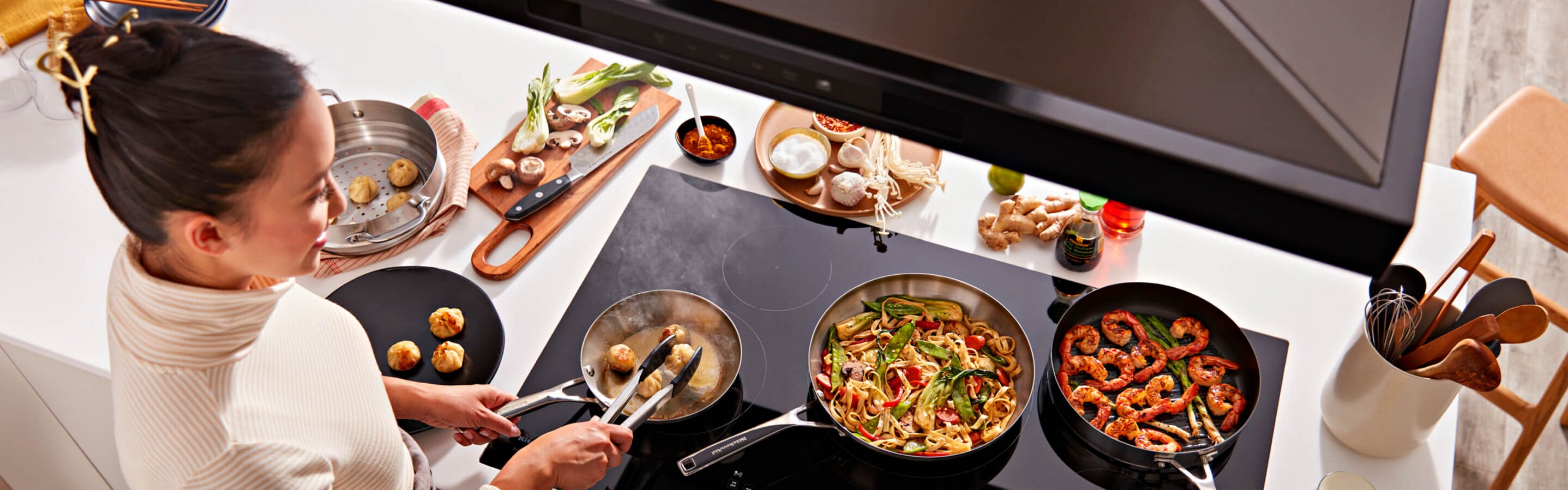 A person searing meatballs on a cooktop.