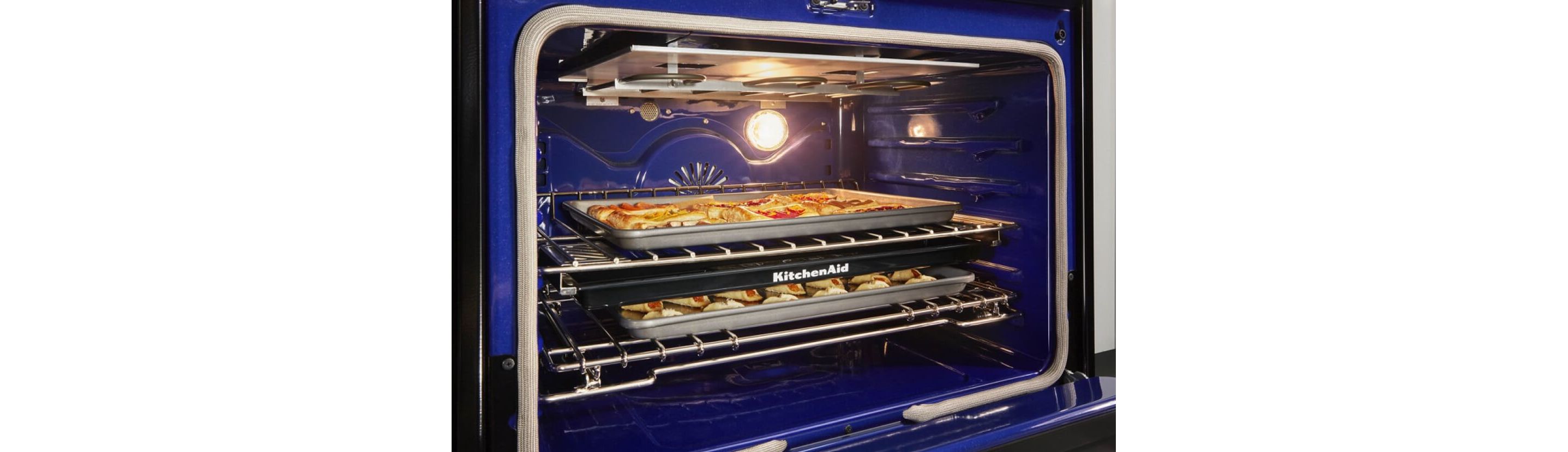 An open oven with trays of food.