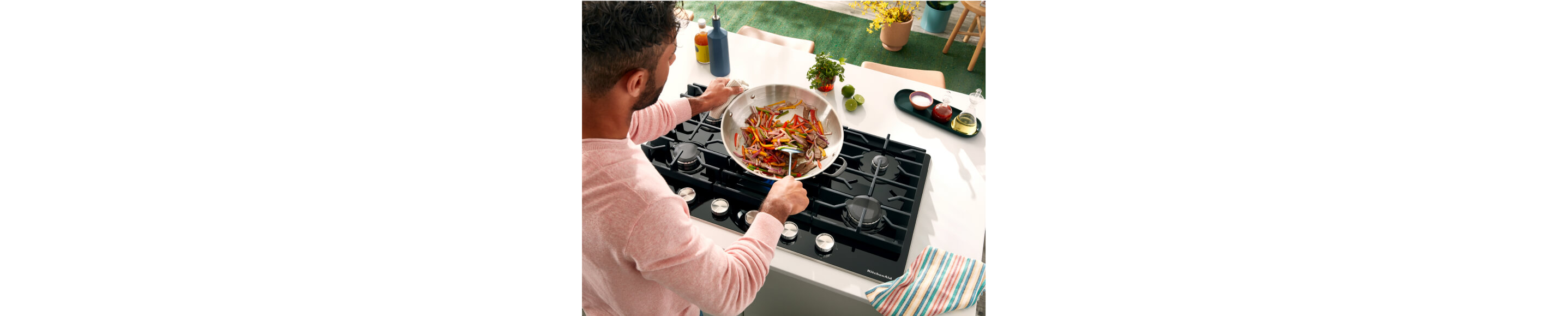 Person sauteing vegetables in a pan over a gas cooktop.