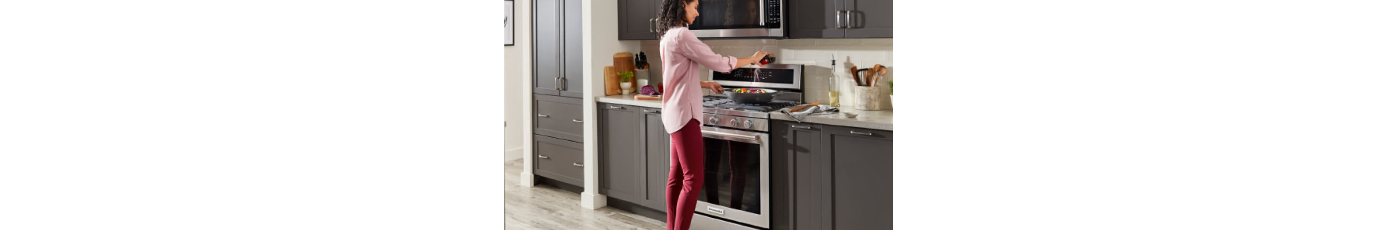 A person preparing a meal on a KitchenAid® Range.