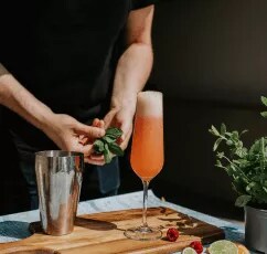 A person making a drink with a garnish.