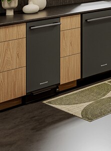 A KitchenAid trash compactor installed within a bank of cabinets.