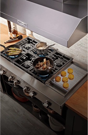 A gas cooktop with three pans of food cooking on it