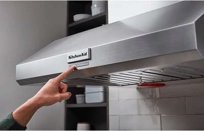A hand adjusting the speed setting on a range hood