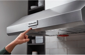 A hand adjusting the speed setting on a range hood