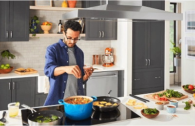 Person adding herbs to a stew with prepped ingredients nearby