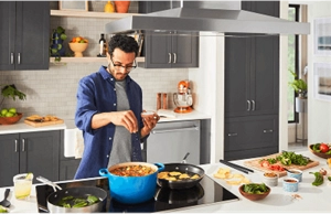 Person adding herbs to a stew with prepped ingredients nearby