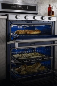 A large KitchenAid® double oven range cooking garlic bread, asparagus and whole chickens inside the oven