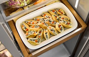 A KitchenAid® refrigerator drawer with a dish of stuffed pasta shells inside.